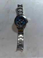 Front view of Armitron stainless steel watch showing blue dial and missing bracelet link at band end.