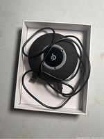 Front view of the round black wireless charging pad with a USB cable coiled on top, showing the Blavor logo and surface details.