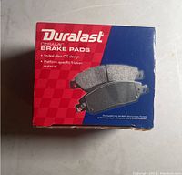 View of the brake pads box front showing product branding and picture of brake pads.