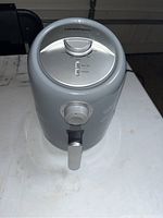 Front view of gray Farberware air fryer showing timer dial, temperature dial, and pull-out basket handle.