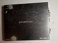 Top view of the black Powerbass ASA 1000.1D amplifier showing brand, model, and 2000 watt rating.