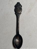 First spoon showing detailed crest with Rolex branding and engraved decorative bowl.