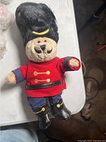 Plush bear doll wearing British guard costume lying on table