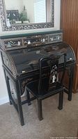 Full view of the black lacquer roll top desk with hand-painted motifs and mother of pearl inlays, showing the curved top and small drawers with decorative knobs.