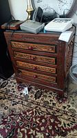 Full front view of the solid wood chest showing all four drawers with carved motifs and glass top.
