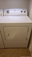 Front view of a white Whirlpool electric dryer showing door and control panel with dial and knobs.
