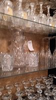 Cut glass drink glasses and crystal wine glasses on shelves showing cut detailing and stemware