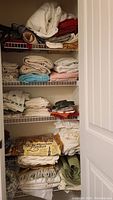 Photo of linen closet shelves showing folded towels, linens in various colors and fabrics.