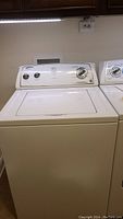 Front view of Whirlpool top load washing machine showing dials and lid.