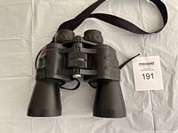Front view of black binoculars showing the eyepiece side, included neck strap, and central focus wheel.