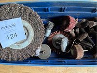 Blue plastic container holding various brake parts, springs, washers, and abrasive wheels including wire brush and flap wheels.