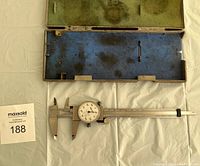 Mitutoyo dial caliper inside open blue-lined case with green interior lid lining