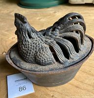 View of the top and side of the cast iron rooster humidifier showing detailed rooster head and tail, and the base container.