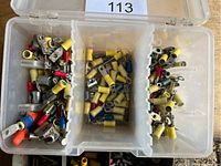 Three-section clear plastic box with assorted insulated electrical connectors including ring and spade terminals in colors yellow, red, blue, and beige.