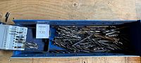 Blue plastic case filled with various metal drill bits of different sizes, showing an assortment neatly organized.