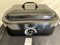 Front view of Proctor Silex electric roast pan showing temperature control dial and handle on lid.