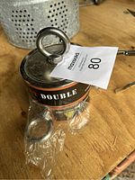 Photo of one fishing magnet with metal eyelet on top, placed on wooden surface with plastic wrapping under it.