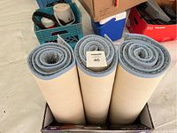 View of the rolled blue floor runners placed in a box, showing the edges and backing.