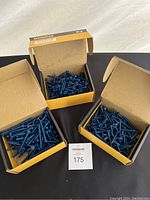 Three open boxes showing blue coated screws inside each box.