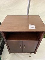 Front view of vintage wooden record storage cabinet with closed doors and open upper shelf.