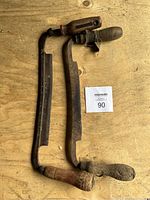 Top-down photo of two older wood shavers lying on a wooden surface, showing handles and blades.