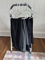 Two pairs of pants on hangers placed on a clothing rack, showing color and fabric texture.
