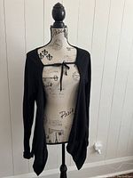 Front view of the black knit cardigan displayed on a mannequin, showing tied front and long sleeves.