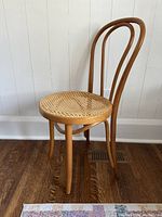 Front view of vintage bentwood chair showing curved backrest and cane seat with sagging.