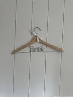 Front view of the natural wood hanger with metal wire 'Bride' decoration and white ribbon tied to the hook.