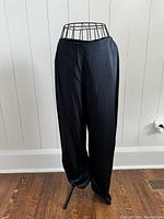 Front view of Donna Karan Signature black pants displayed on a wire mannequin to show full length and fit.