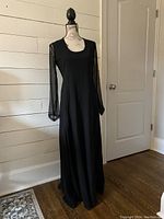 Front view of black Dries van Noten wool dress on mannequin with sheer long sleeves