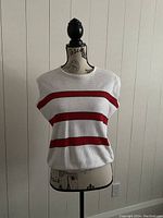 Front view of the Marni sleeveless knit top showing white color with three red horizontal stripes, round neckline, and textured knit fabric on a mannequin.