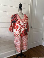 Mannequin wearing reversible jacket and dress set showing front view with patterns and length.