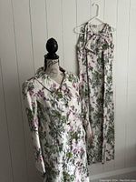 Side view of floral overcoat on mannequin and sleeveless dress hanging on wall