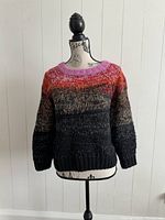 Front view of the multicolor knit sweater on a mannequin, showing pink rounded collar and striped pattern with metallic threads.