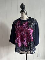 Front view of Talbot Runhof women's shirt displayed on mannequin, showing black lace with bright pink floral embroidery overlay on solid black fabric arms and back.