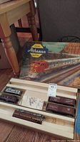 Full view of open wooden tray with Athearn HO scale model train cars inside and the box lid with colorful train illustration and logo in background.