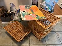 Wide view showing two wicker baskets, one with lid, and a colorful plastic summer tray on top.