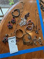 Overview of various costume jewelry items including necklaces, bracelets, earrings arranged on a wooden table.