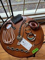 Full lot showing necklaces, bracelets, and Coach wallet on a wooden table.