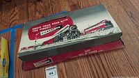 Original Gilbert HO model train box with vintage artwork showing steam and diesel locomotives, including 'Equip your road with the finest! Gilbert HO' slogan