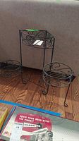 Folding metal corner plant stand showing overall structure and three leg base with one pull out circular tray