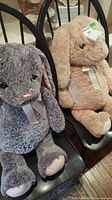 Both plush rabbit stuffed animals seated on black chairs, showing size and condition.