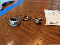 Three sterling silver rings displayed on wood surface, showing overall difference in styles and sizes.