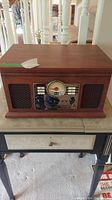 Victrola vintage stereo in wooden cabinet on small table, showing overall unit with speakers and radio tuner.