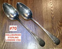 Two Georgian sterling silver serving spoons placed on wooden surface showing full length.
