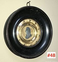 Full front view of circular plaque showing frame, glass, and central medallion
