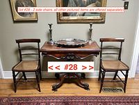 Pair of Late Victorian side chairs flanking an antique table, placed on hardwood floor beneath wall artworks