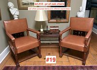 Two oak armchairs side by side with small table in between on wood floor