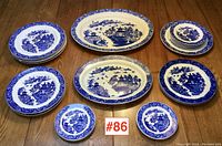 Group shot of all Blue Willow platters and plates arranged on wood floor.